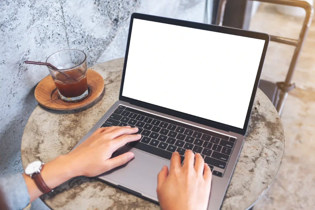 Woman typing on laptop at café, symbolizing remote opportunities in technical SEO specialist jobs.