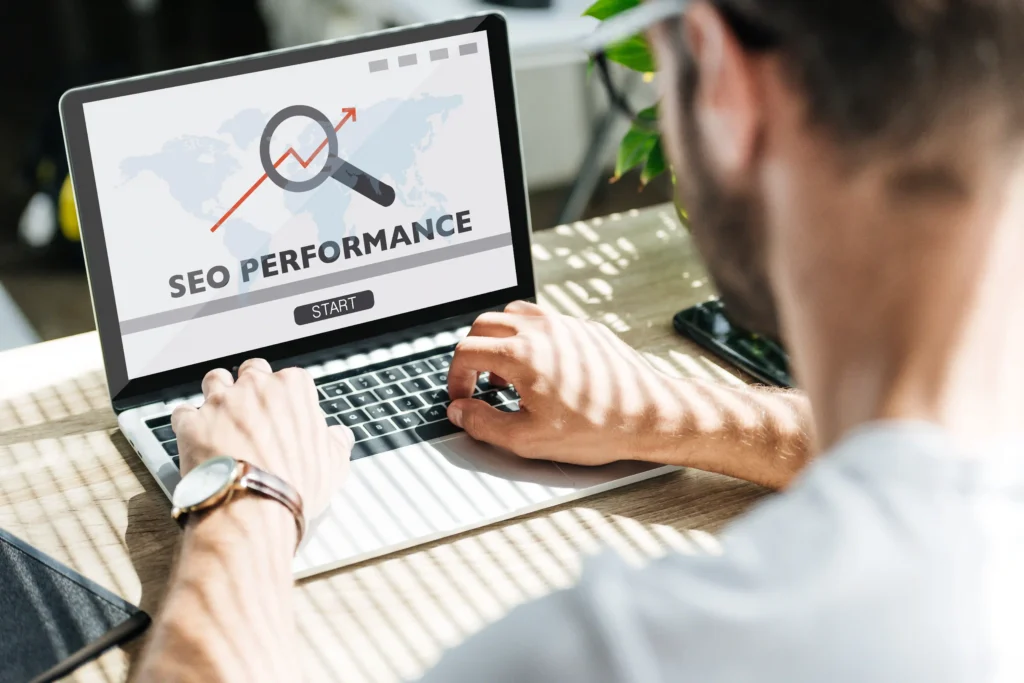 Back view of a developer analyzing SEO audit performance metrics on a laptop screen.