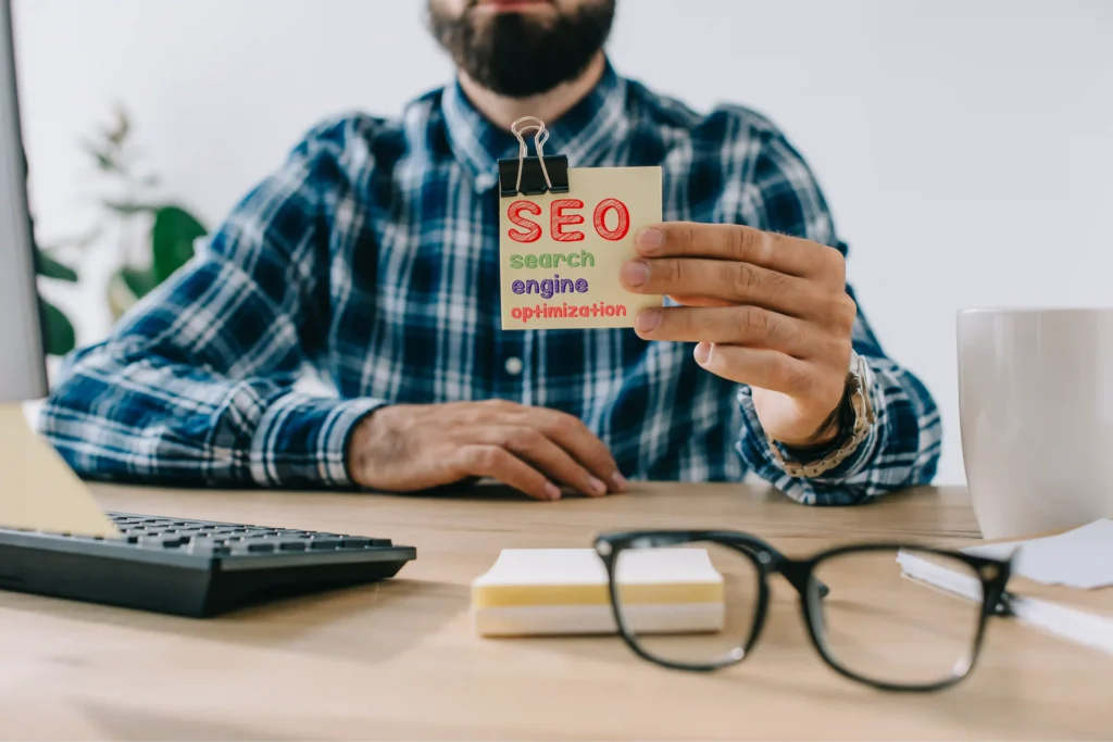 Developer holding a note on International SEO practices at workspace with coffee and keyboard