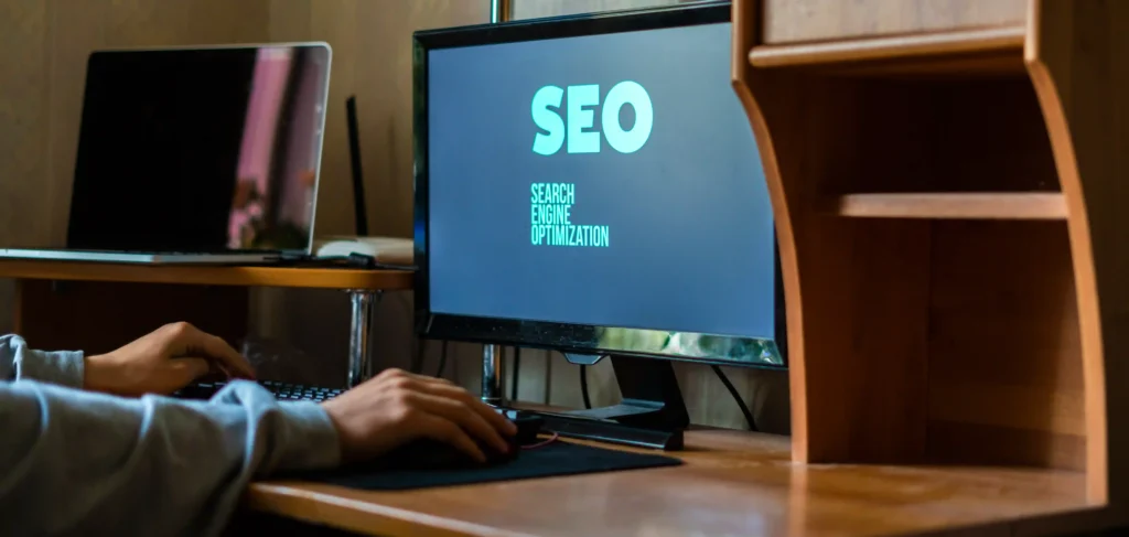 Person working at a desktop displaying the phrase 'Search Engine Optimization', representing technical SEO specialist jobs.