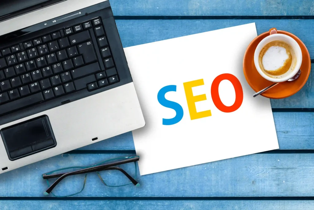 Flat lay of laptop, coffee, and technical SEO roadmap notes on a blue desk
