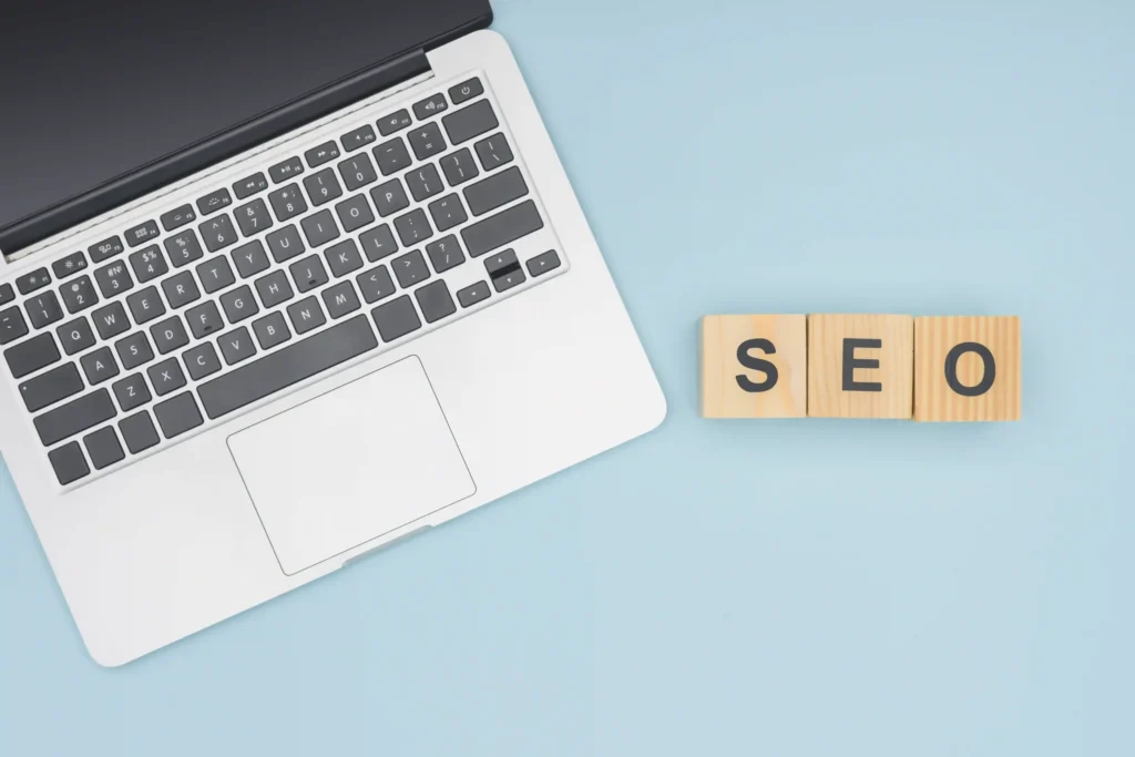 Top view of laptop next to wooden blocks spelling SEO, symbolizing on page SEO tutorial PDF setup