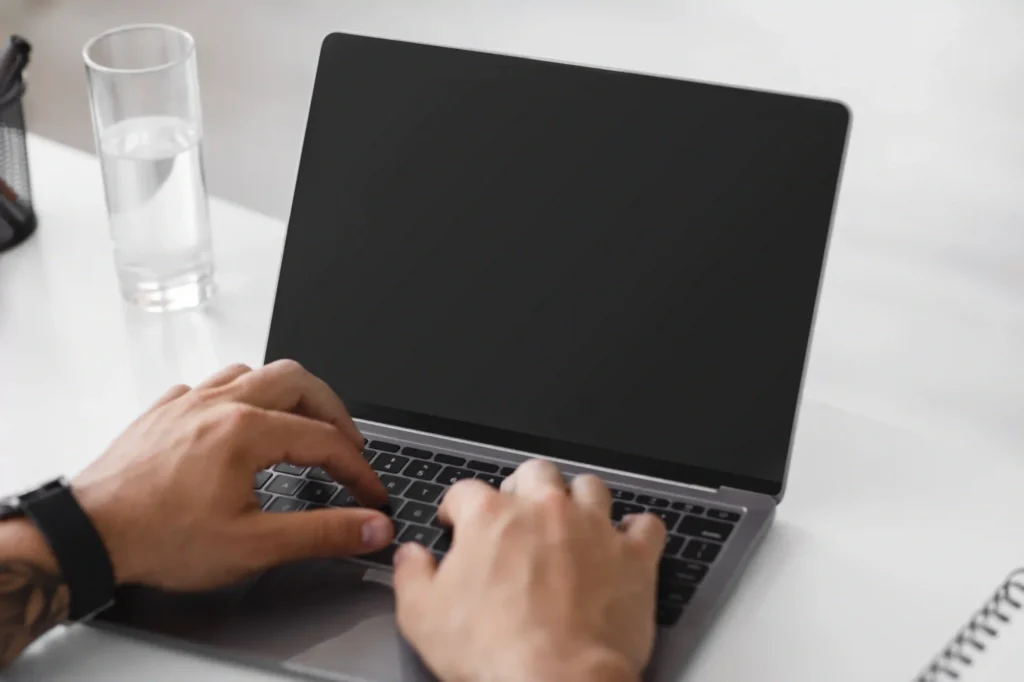 Man typing on a black laptop at a clean workspace, illustrating modern technical SEO specialist jobs in action.