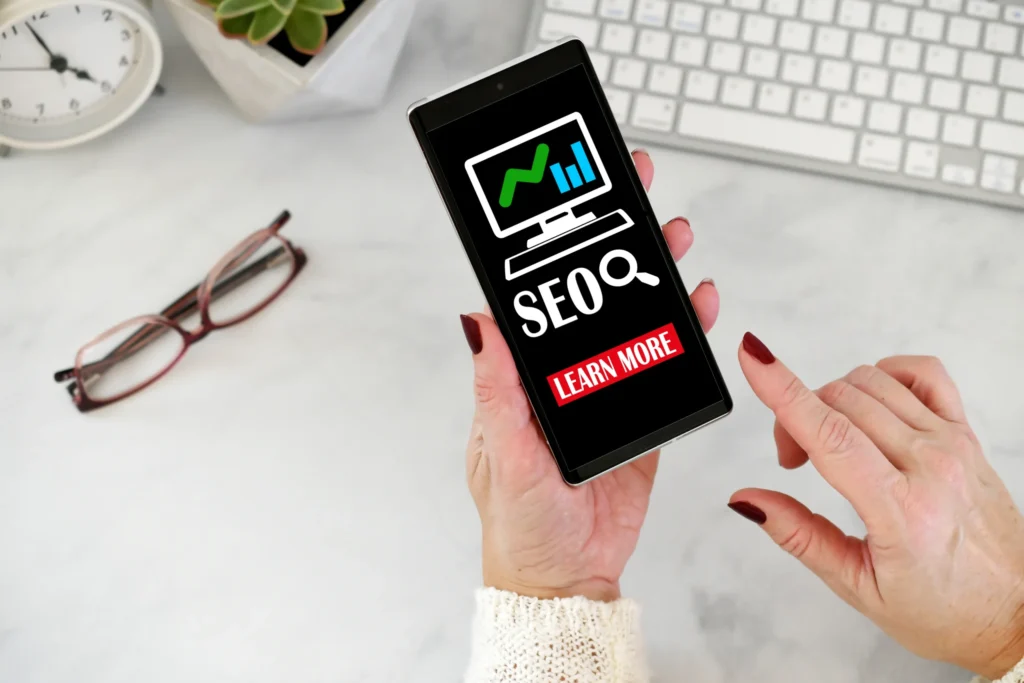 Mobile phone showing SEO concept with the words “Learn More,” reflecting seo marketing free tools online.