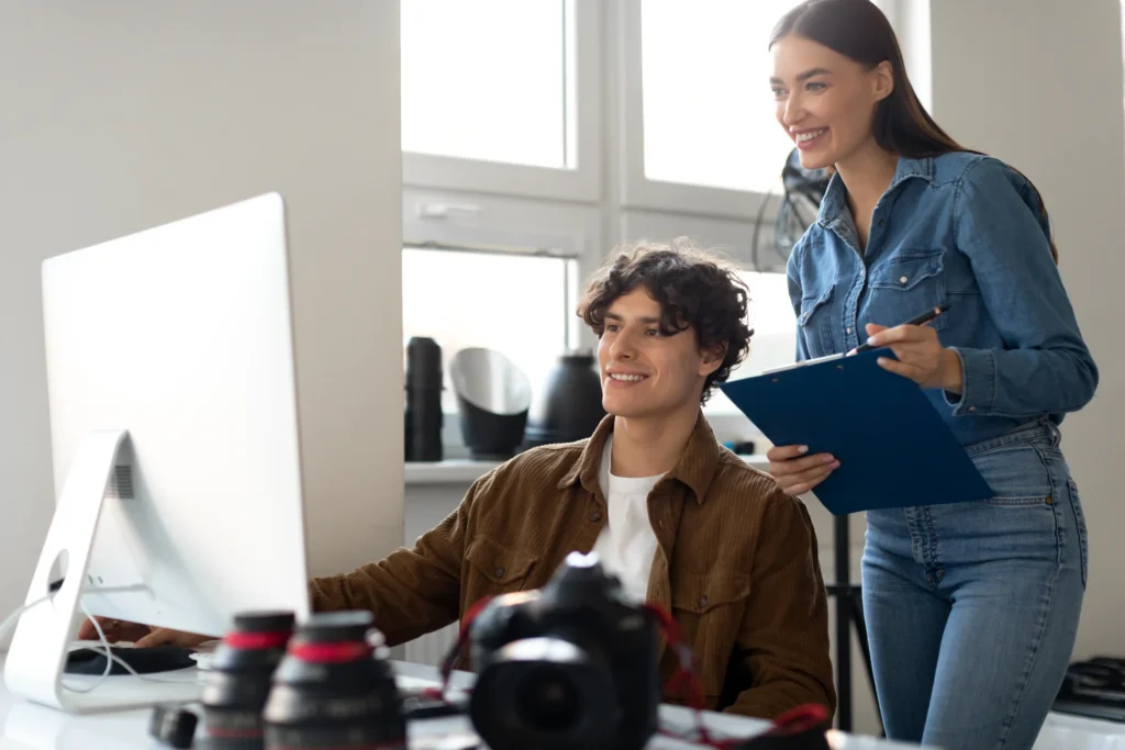 Two creative professionals discussing an seo services template on screen in a modern office setting.