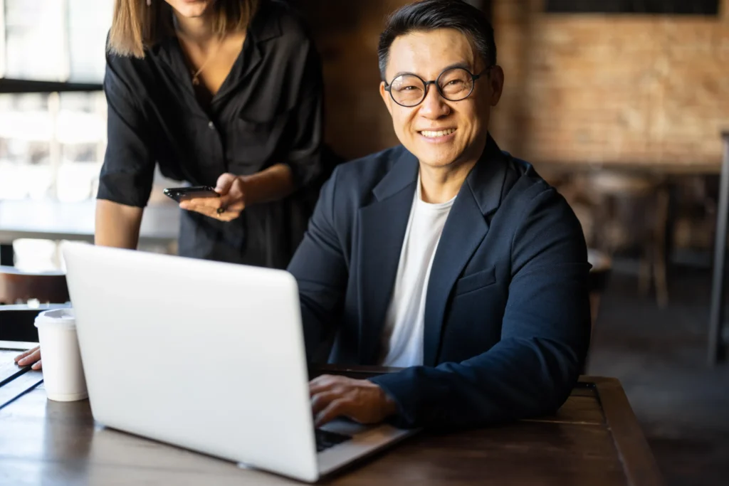 Smiling digital marketing professional working on a laptop in a cafe, representing remote work for seo business online.