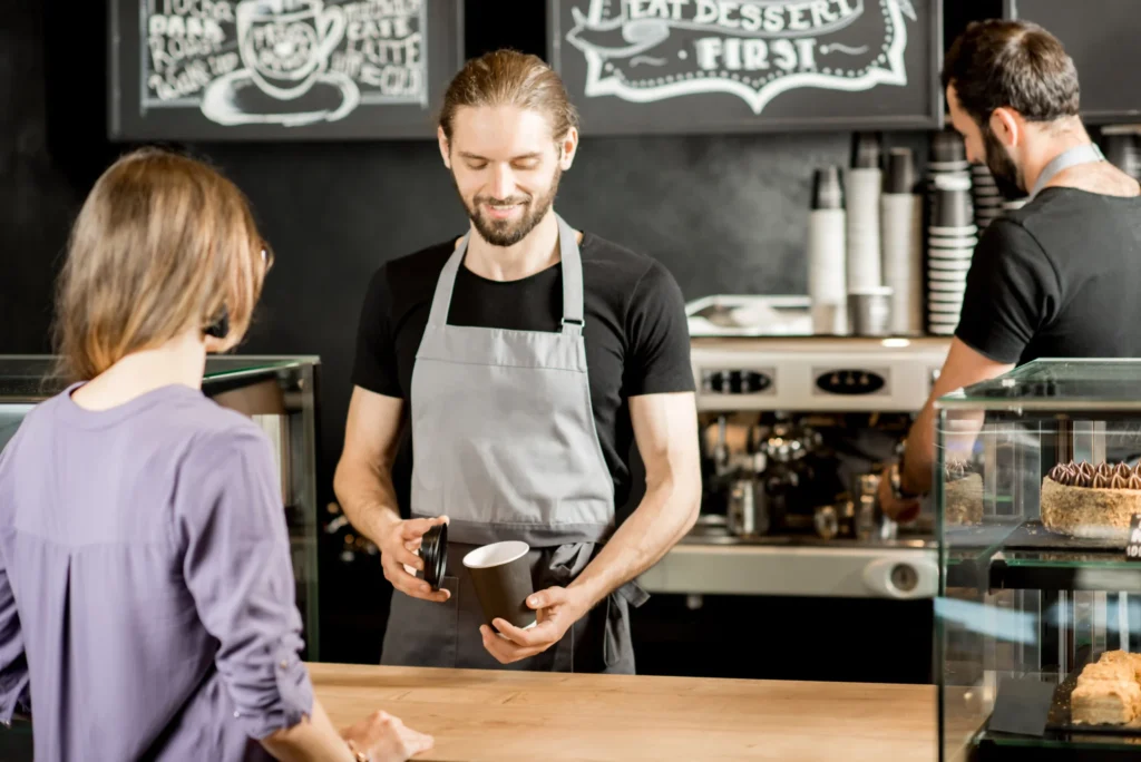 Barista serving a customer at a local café counter, demonstrating personalized service for coffee campaign ideas.