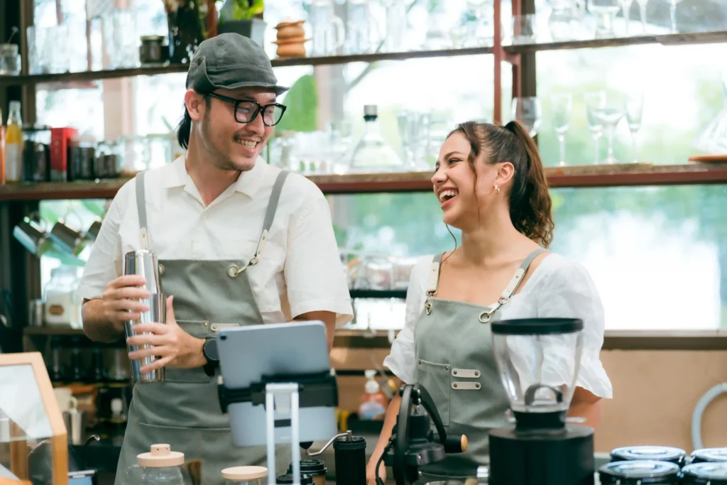 Baristas smiling and preparing drinks in a café, illustrating how restaurant social media marketing companies capture authentic hospitality moments.