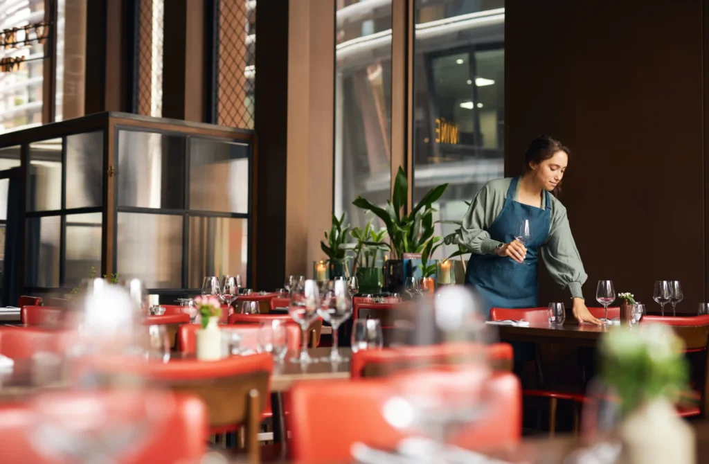Female waitress preparing tables in an elegant dining area, showing real-world impact of restaurant search engine marketing on local traffic.