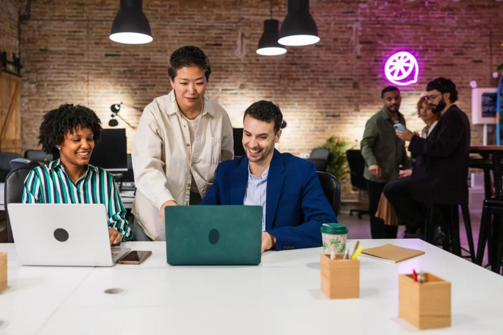 Diverse team collaborating with laptops and strategy notes in a modern workspace at an affordable digital marketing company.