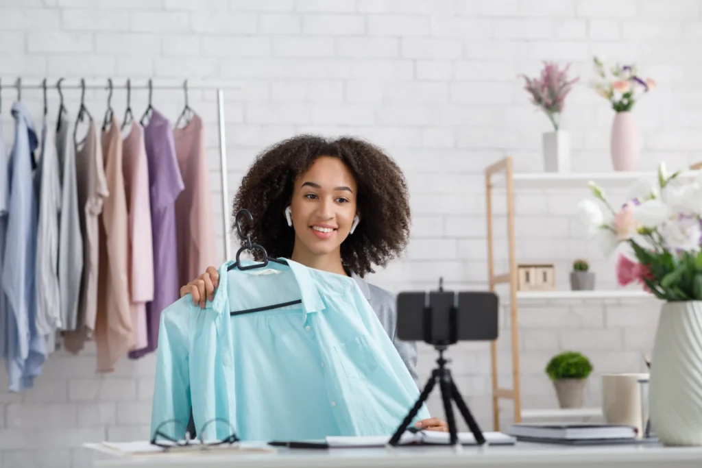 Fashion creator showcasing a blue blouse on camera for her clothing brand, guided by an online boutique marketing agency.