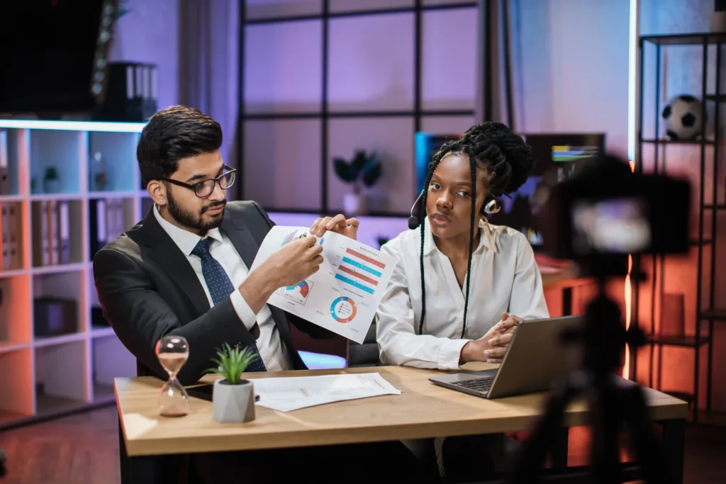 Two marketing professionals reviewing campaign charts and analytics during a strategy meeting for performance marketing services.