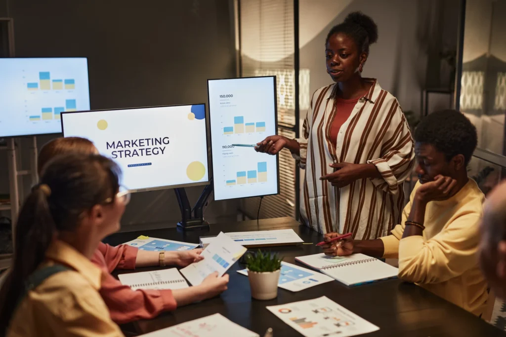 Marketing strategist presenting data dashboards and campaign insights to a team while discussing performance marketing services.