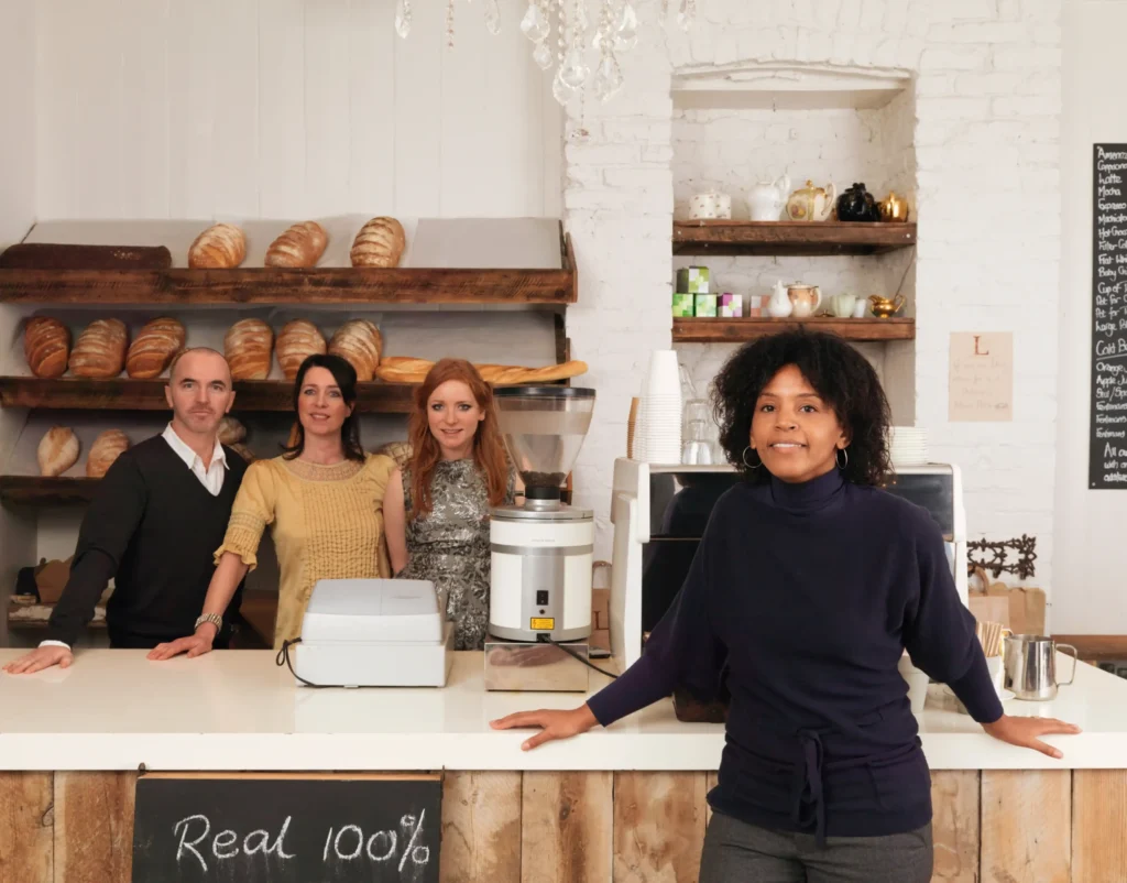 A group of small business owners standing behind a bakery counter, representing local companies that benefit from local search optimization services.