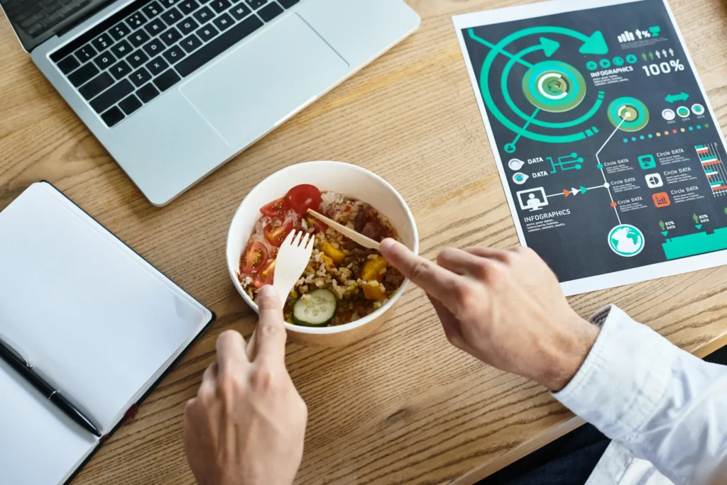 Entrepreneur enjoying lunch while analyzing marketing data — concept of food digital marketing productivity.