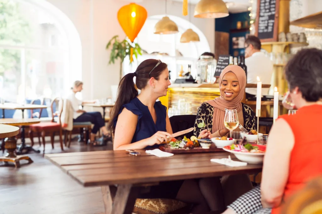 Two women enjoying lunch in a modern restaurant, representing customer engagement and loyalty strategies from a digital agency for restaurant marketing.