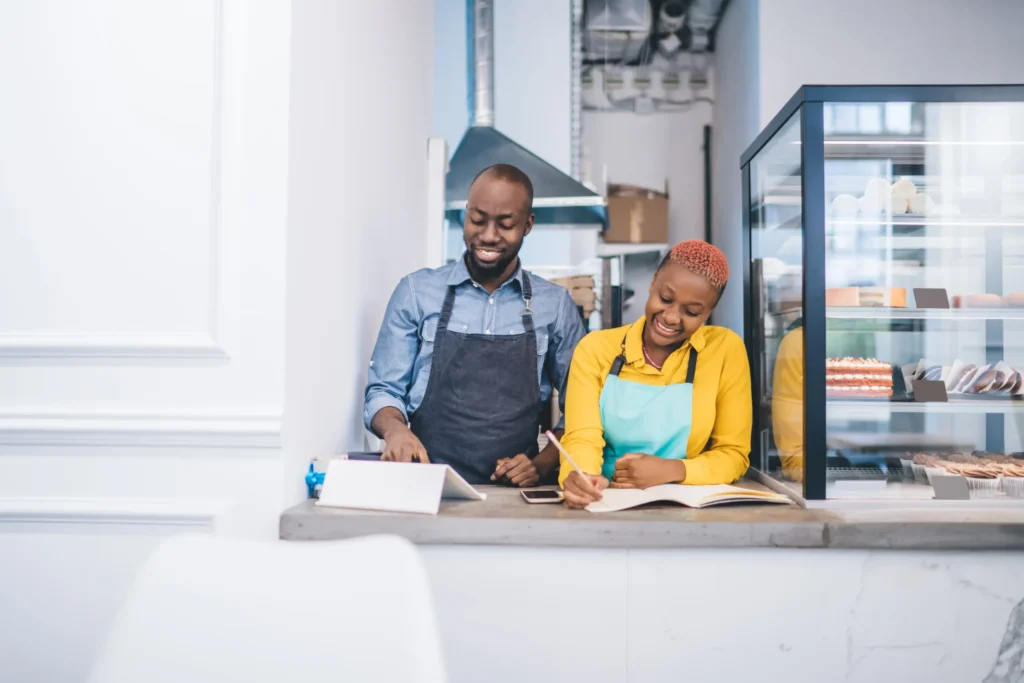 Two café owners reviewing notes at their counter, showing how local search optimization services help small businesses grow.