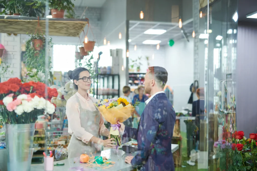 Florist handing a bouquet to a customer, demonstrating how local search optimization services increase in-store visits.