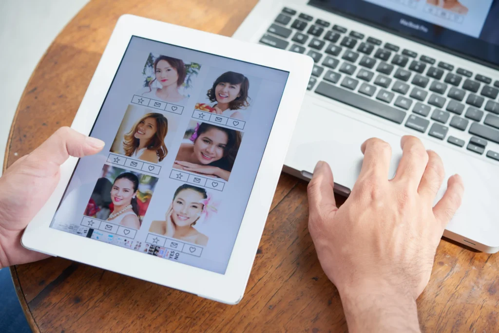 Person browsing profile images on a tablet beside a laptop, illustrating digital engagement and user interaction connected to the best online marketing services.