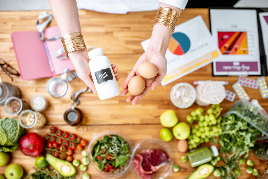 Dietitian showcasing healthy ingredients like milk and eggs on a table filled with fresh produce for food marketing ideas and nutrition branding.