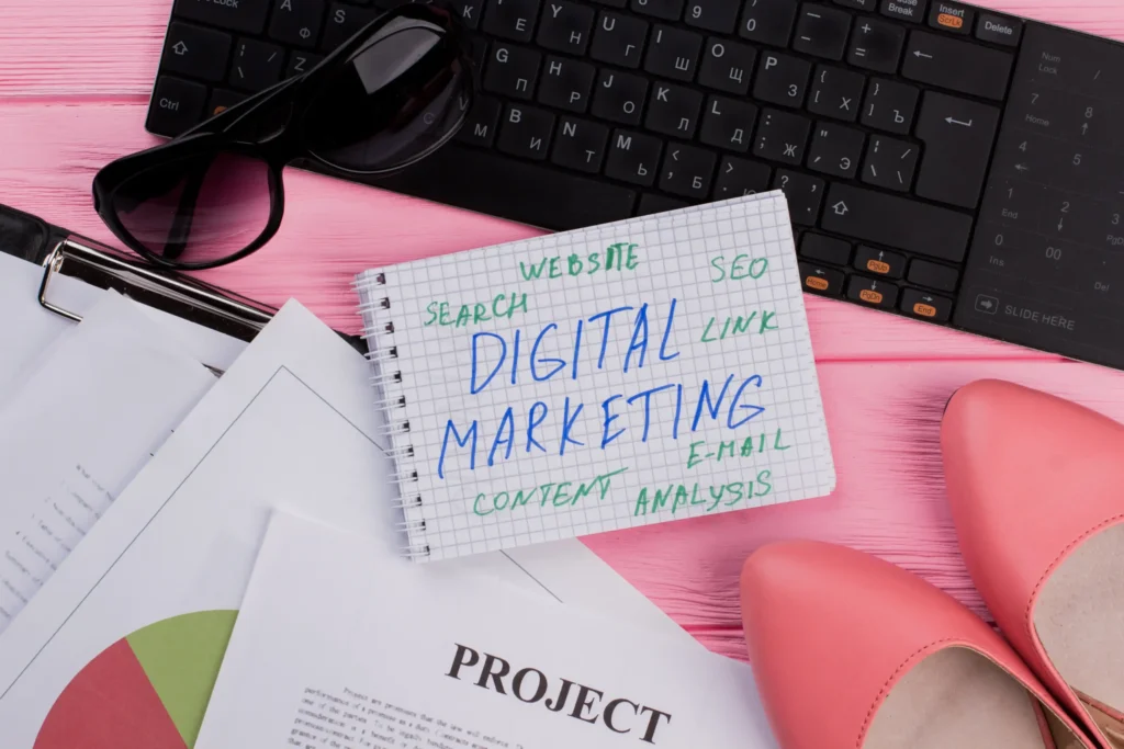 Flat lay workspace with notebook showing SEO, content, and email strategy ideas for digital marketing solutions for small businesses.