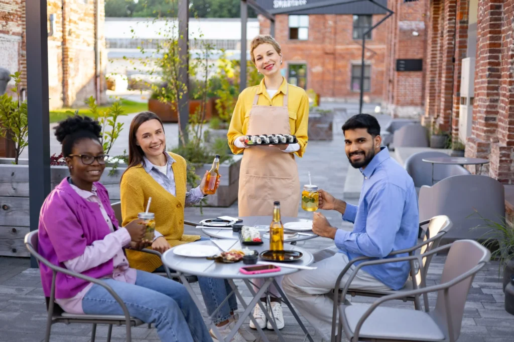 Group of friends enjoying food and drinks at an outdoor restaurant, showcasing customer engagement that restaurants online marketing can attract.