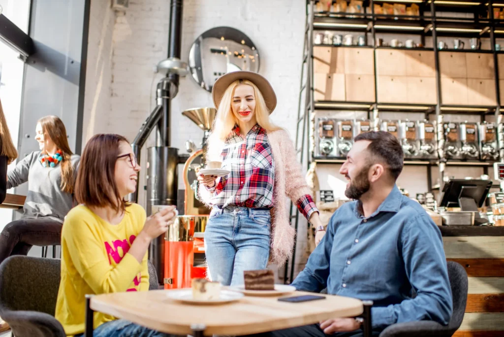 Group of friends enjoying coffee and dessert in a bright café, illustrating social and community-based unique restaurant promotion ideas.
