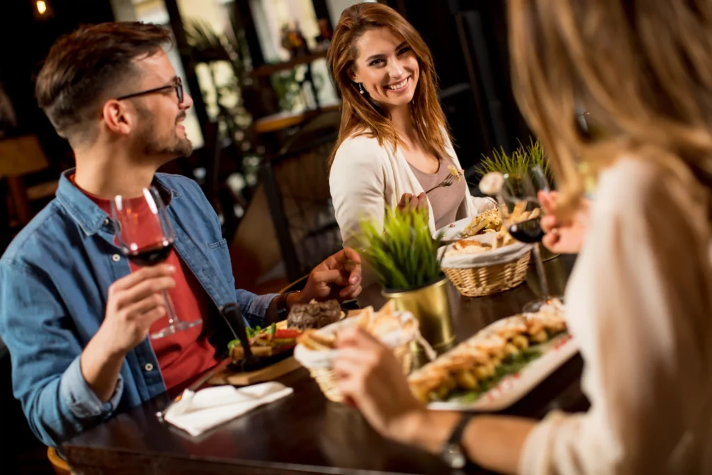 Young adults enjoying dinner at a cozy restaurant, reflecting authentic customer moments in a social media strategy for restaurant.