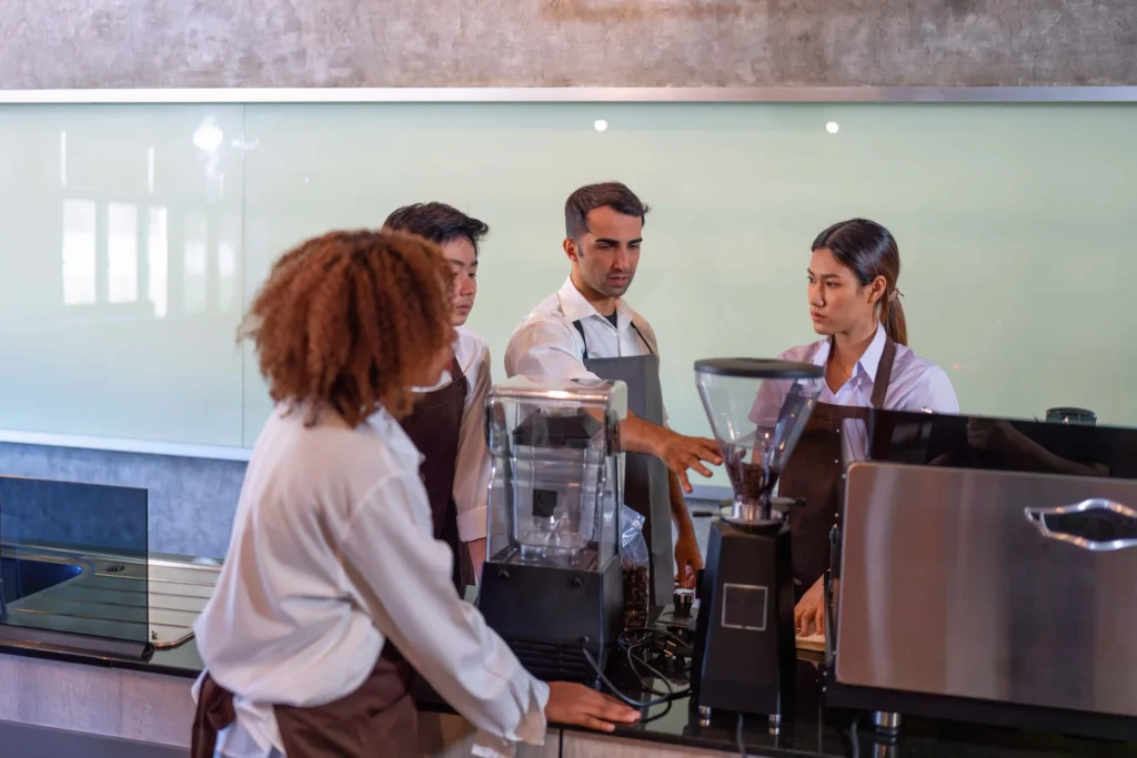 Café team learning espresso skills together as part of creative staff training and coffee advertising ideas for cafés.