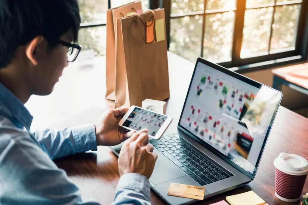 Man shopping online with laptop and smartphone, reflecting digital experience design guided by an ecommerce branding agency.
