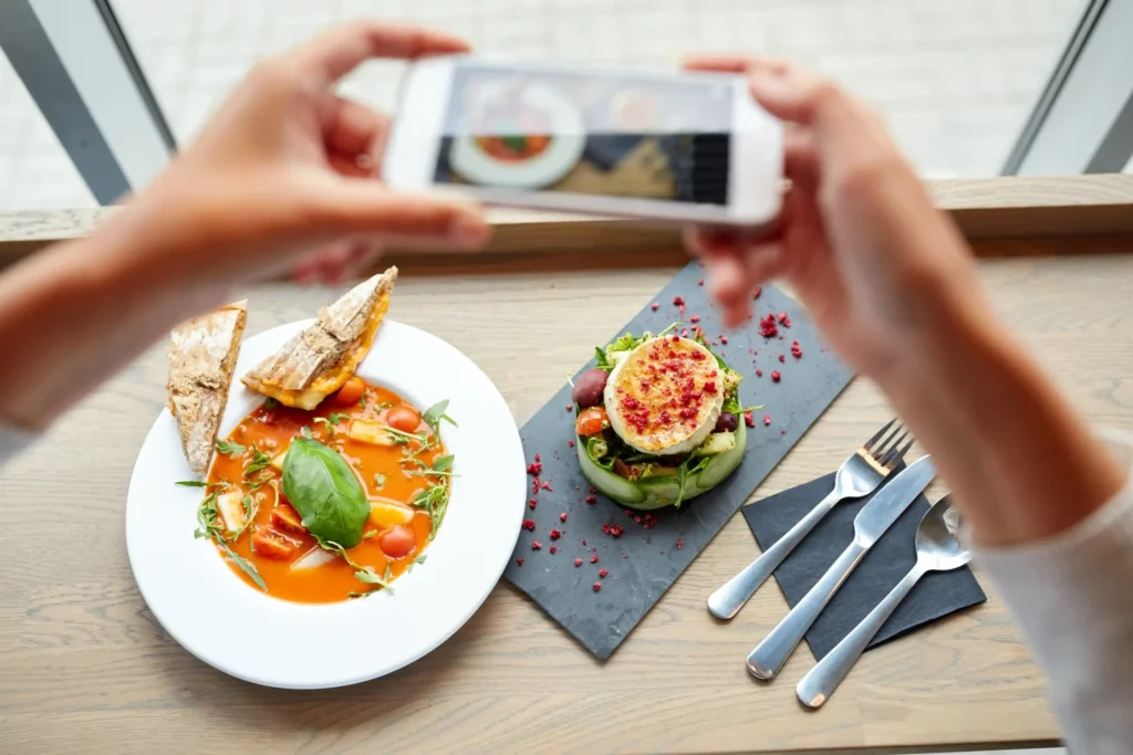 Hands photographing a gourmet dish for social media as part of digital marketing food and beverage promotion.
