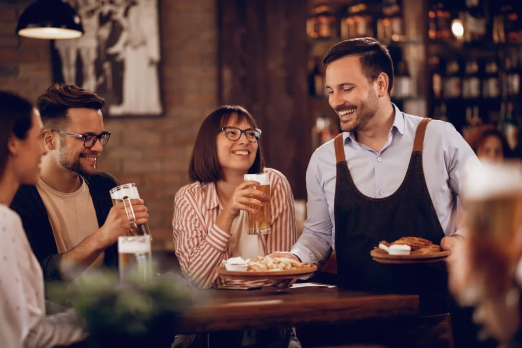 Happy customers being served at a busy restaurant, showing the results of effective marketing services for restaurants.