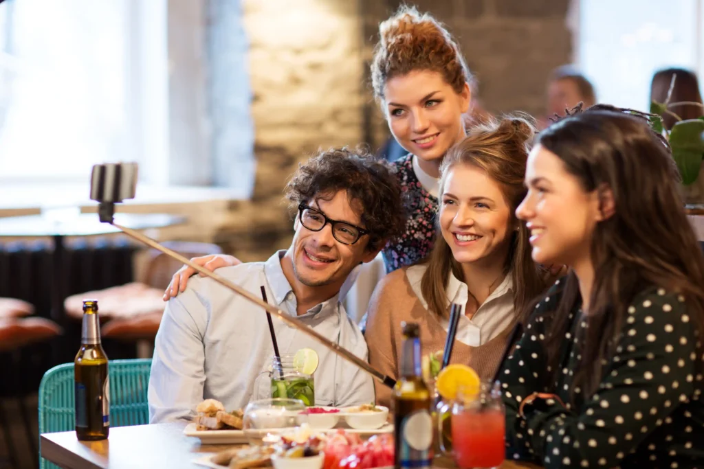 Young adults capturing moments over dinner, representing social media content ideas from a digital marketing plan for restaurant owners.