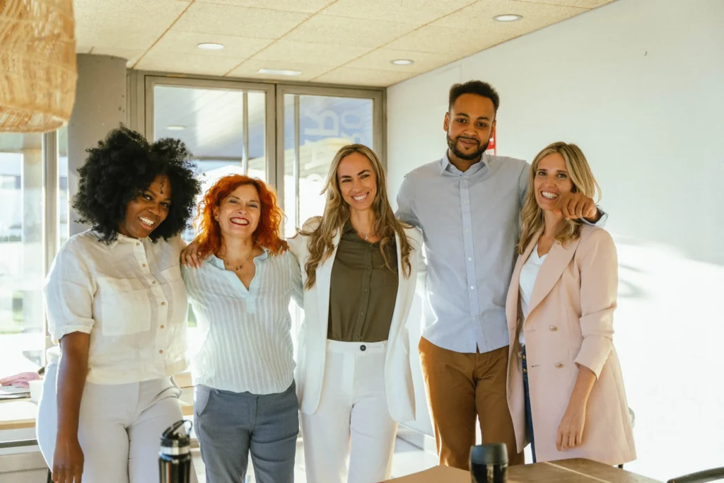 Diverse team members at a web design and marketing agency smiling together in a modern office environment.