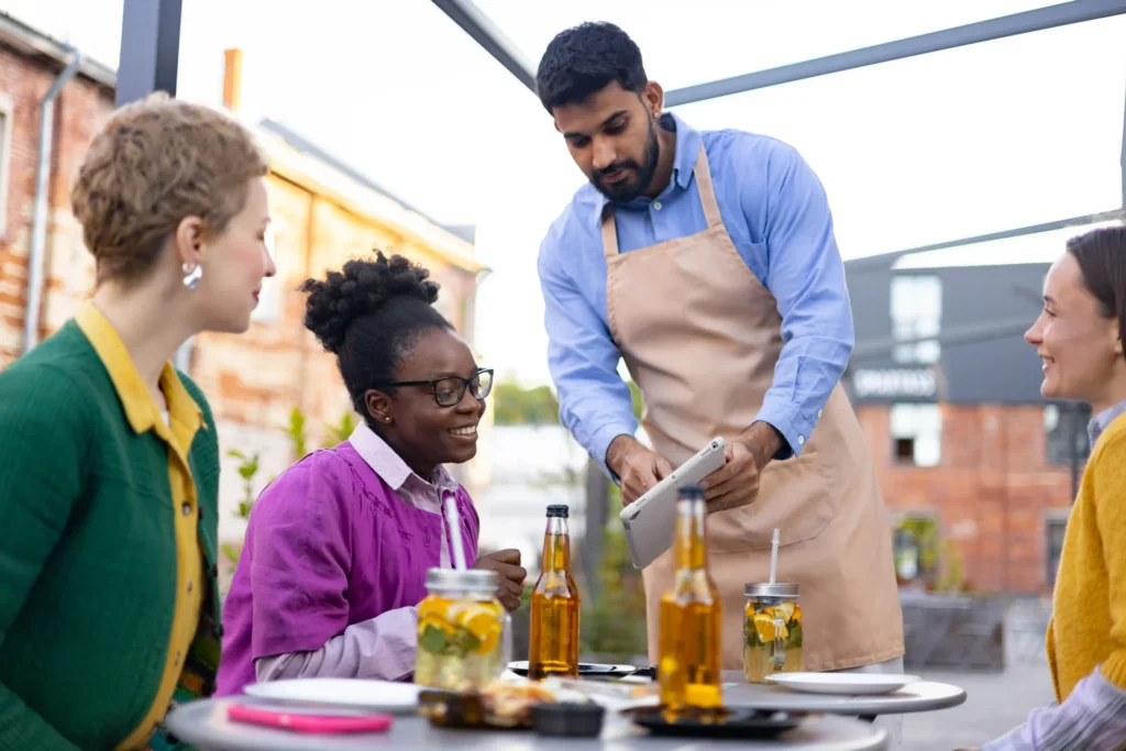 Server assisting guests at an outdoor café, reflecting how marketing services for restaurants improve guest interactions and traffic.