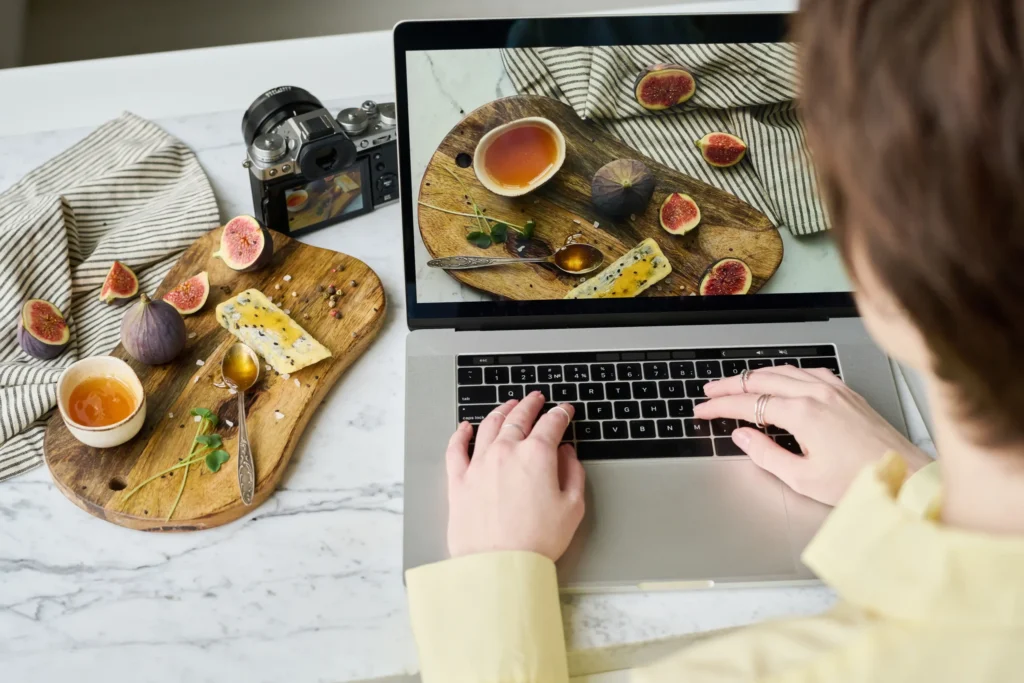 Digital marketer editing food photos on a laptop to prepare visuals for food digital marketing content.