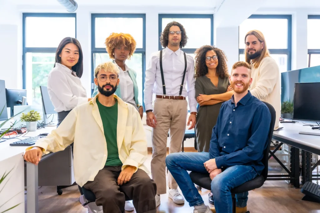 A diverse group of young marketing professionals posing in a modern office, showcasing the collaborative culture of a boutique social media agency.