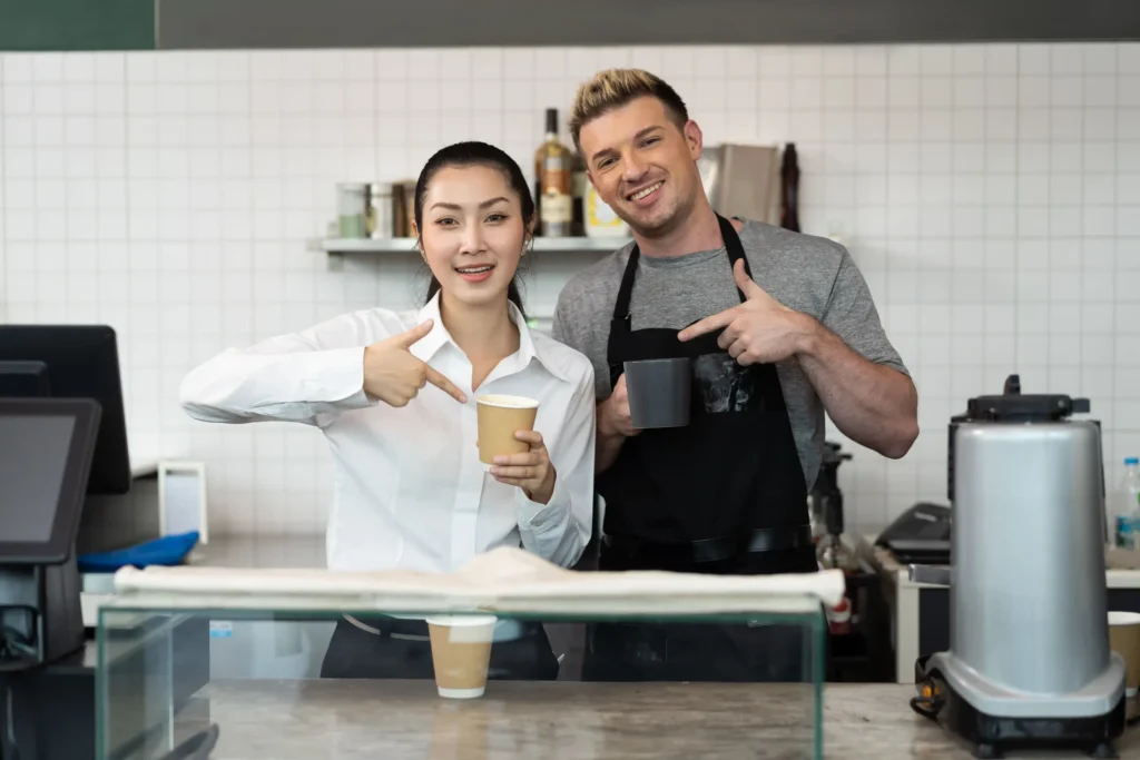 Baristas presenting takeaway coffee cups as part of a cafe marketing plan concept.