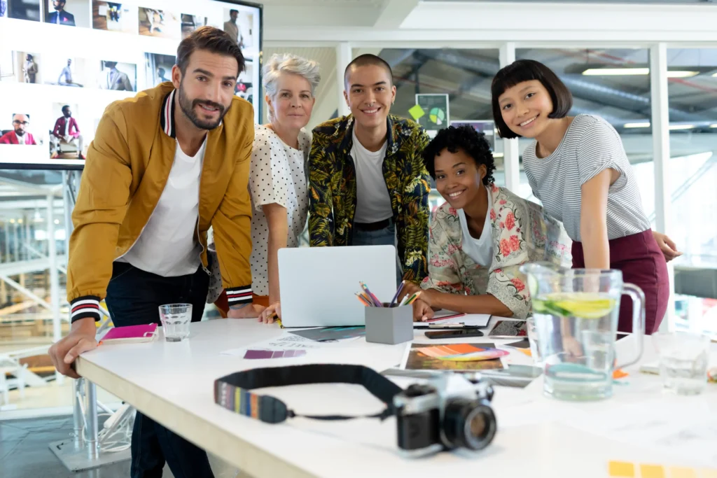 Diverse creative professionals gathered around a laptop during campaign planning, reflecting innovation in top performance marketing agencies.