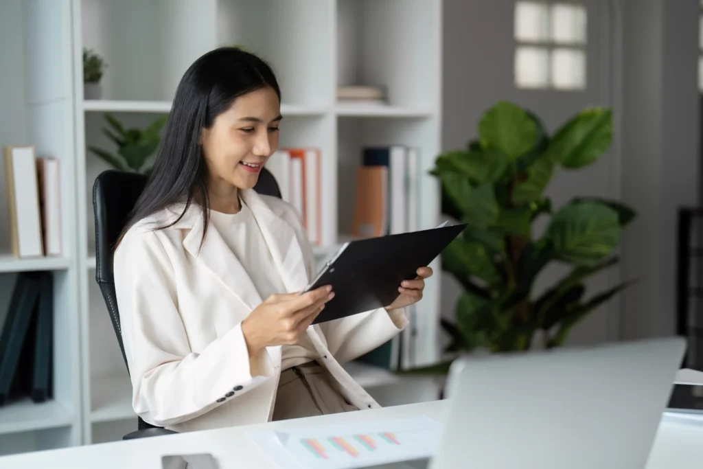 A marketing professional at a digital media marketing company reviewing campaign reports and performance documents at her desk.