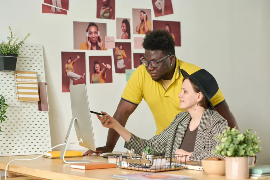 Two creative professionals reviewing visuals on a desktop screen, illustrating professional digital marketing services such as branding, content creation, and campaign design.