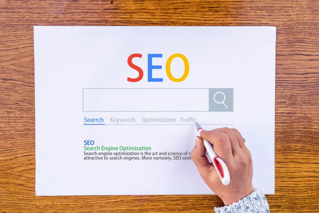 A hand marking keywords on an SEO search bar graphic, representing how businesses look for a seo service company near me to optimize rankings.