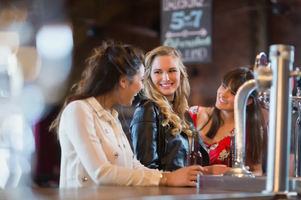 Group of friends smiling and chatting at a bar counter, perfect example of content for social media marketing for bars.