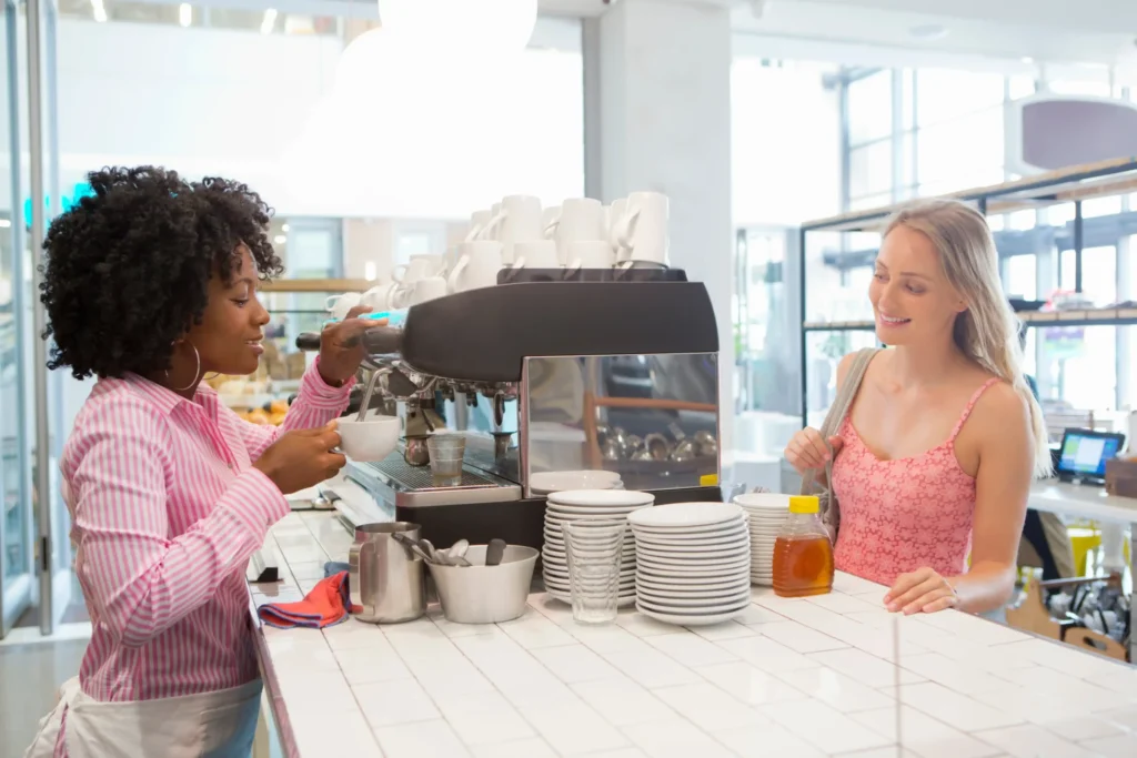 Barista preparing coffee for a guest at the counter, symbolizing personalized cafe ideas to attract customers and improve service.