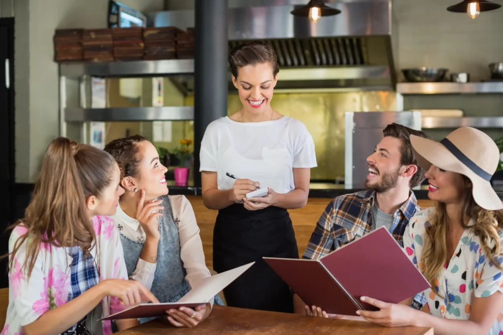 Waitress smiling while taking an order from guests, showing how positive experiences and reviews drive SEO marketing for restaurants.