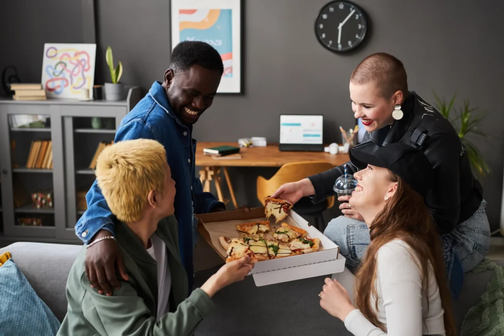 Friends laughing and sharing pizza, symbolizing community engagement and loyalty in pizza marketing ideas.