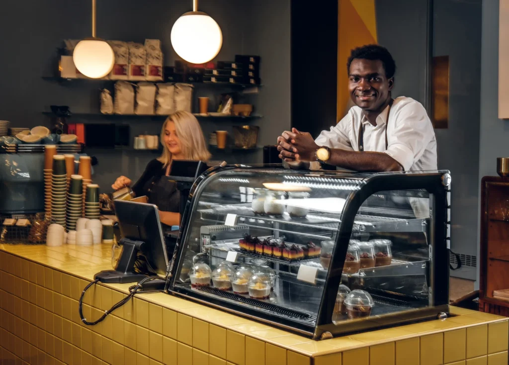 Baristas working behind the counter at a modern cafe, highlighting the operational and branding elements within the marketing strategy of a cafe.