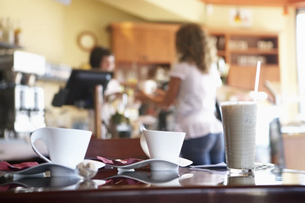 Barista serving a smiling customer in a bright coffee shop, representing excellent service as part of a strong marketing strategy for coffee shop loyalty.