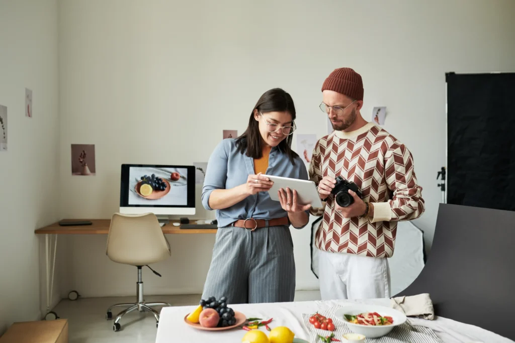 Team reviewing food photography on a tablet during a creative shoot for a restaurant marketing agency near me.