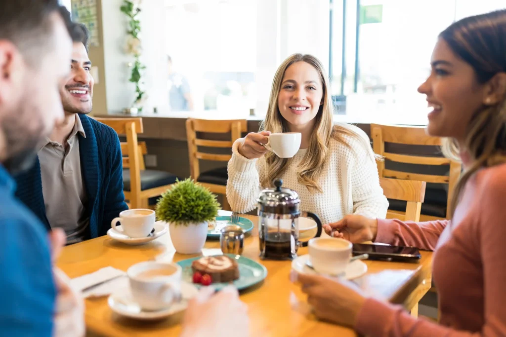 Group of friends enjoying coffee together at a bright café, reflecting customer connection and brand loyalty.